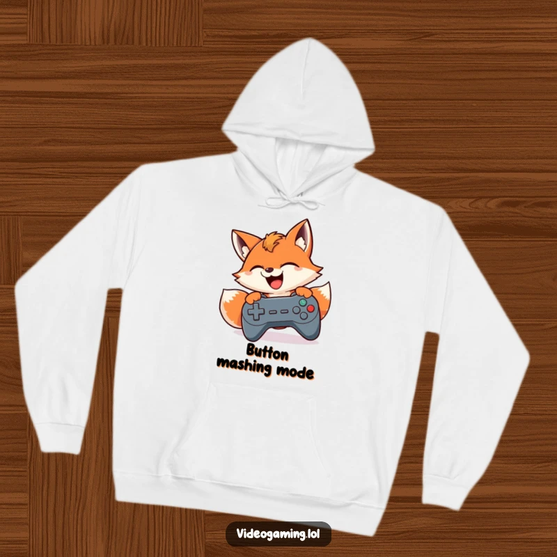Funny hoodie depicting a smiling fox frantically pressing buttons on a game controller, ready for any gaming challenge.